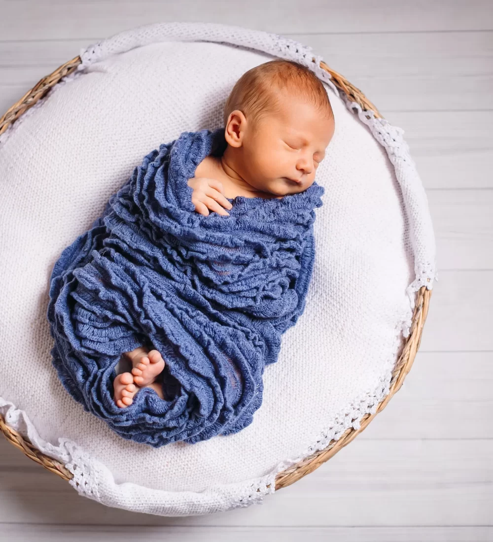 newborn-baby-enveloped-blue-scarf-sleeps-white-pillow_16_11zon